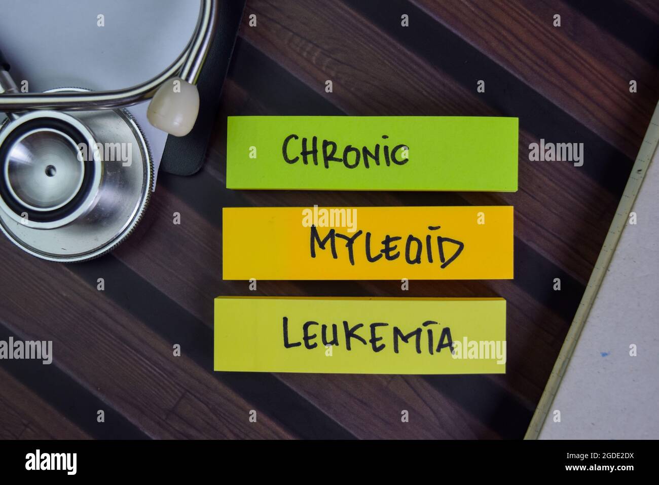 Leucemia micleoide cronica scrivere su note appiccicose isolate su tavola di legno. Foto Stock