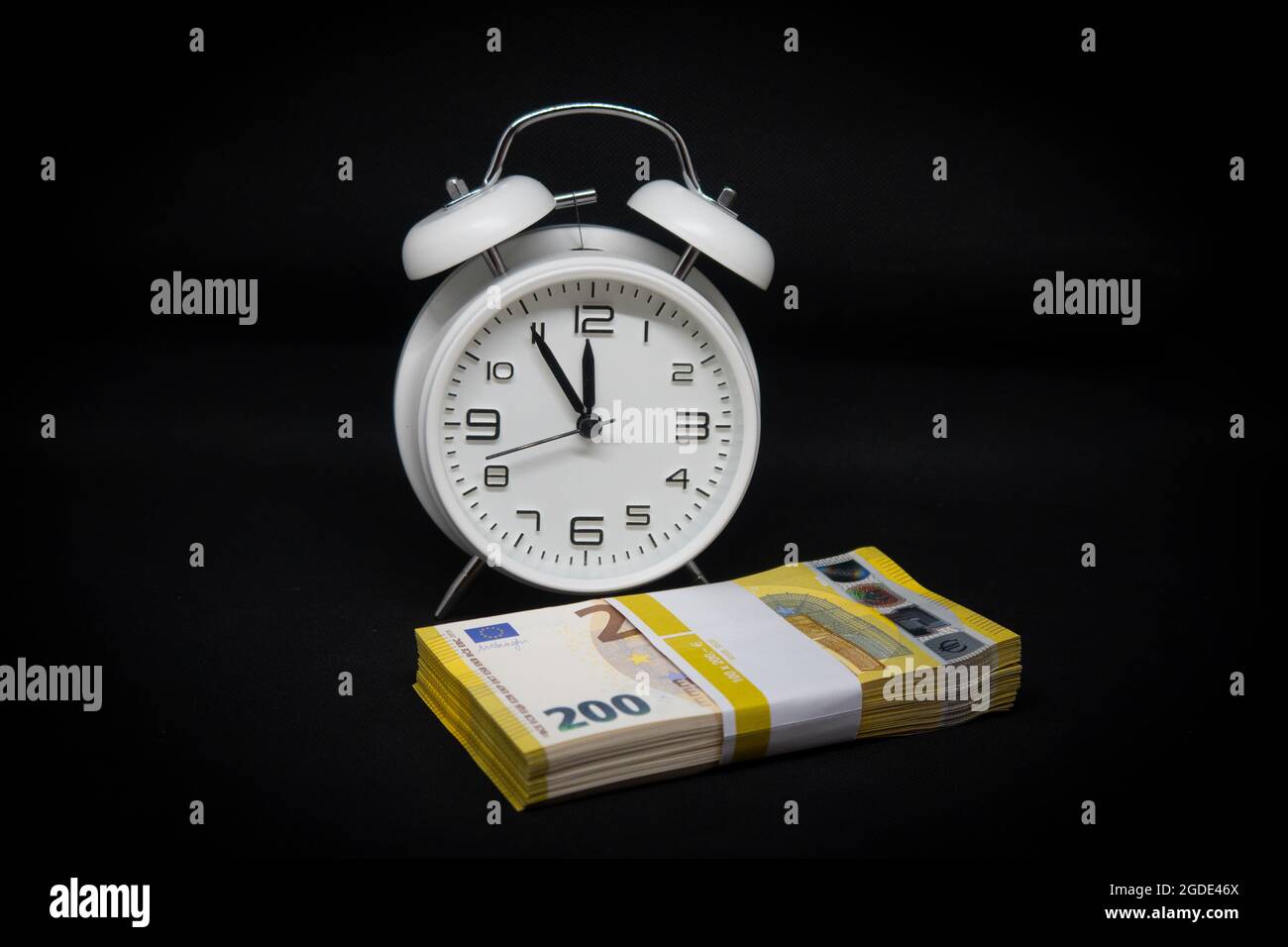 un pacco di banconote da 200 euro si trova di fronte a un orologio bianco  con le mani impostate a 5 minuti a 12 Foto stock - Alamy