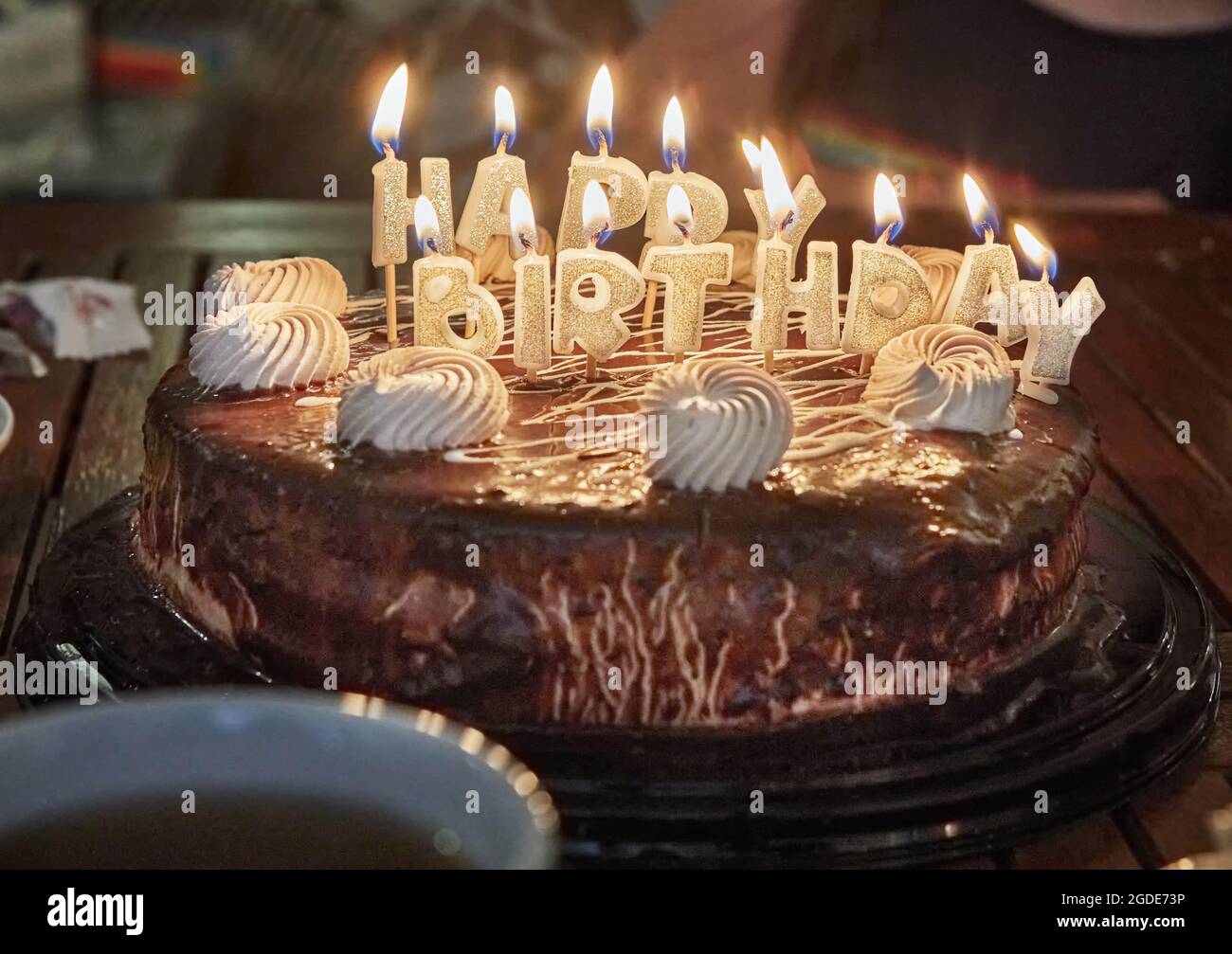 Torta con l'iscrizione buon compleanno con candele brucianti. Foto Stock