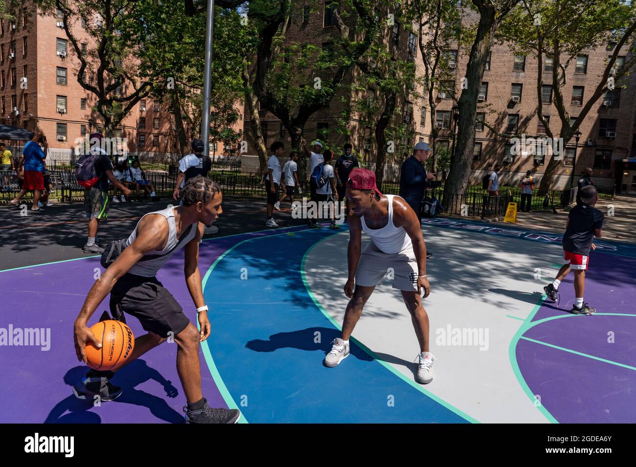 New York, Stati Uniti. 12 agosto 2021. NEW YORK, NY - 12 AGOSTO: La gente gioca a pallacanestro ad un evento di apertura di Queensbridge Houses Basketball Court il 12 agosto 2021 nel Queens Borough di New York City. Il New York Police Department rinnova il campo di pallacanestro presso le NYCHA Queensbridge Houses attraverso l'uso di fondi per le confische. È uno dei 15 campi da pallacanestro in tutta la città che il NYPD sta rinnovando. Il progetto da 4 milioni di dollari è finanziato da busti di farmaci. Credit: Ron Adar/Alamy Live News Foto Stock