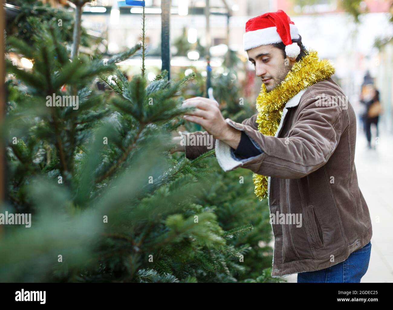 Ritratto dell'uomo gioioso che sceglie i giocattoli e l'albero di Natale a fiera Foto Stock