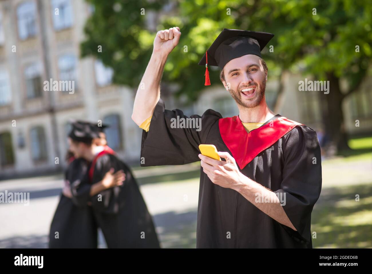 Tall felice graduate testando e guardando eccitato Foto Stock