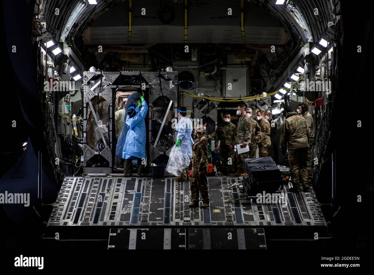 Gli aeristi si preparano a scaricare i pazienti COVID-19 durante il primo utilizzo operativo del sistema di isolamento del trasporto alla base aerea di Ramstein, Germania, 10 aprile 2020. Il TIS è un'unità di contenimento delle malattie infettive progettata per ridurre al minimo il rischio di contaminazione per l'equipaggio e gli assistenti medici, consentendo al contempo l'assistenza medica a bordo per i pazienti affetti da una malattia. (STATI UNITI Air Force foto di staff Sgt. Devin Nothstine) Foto Stock