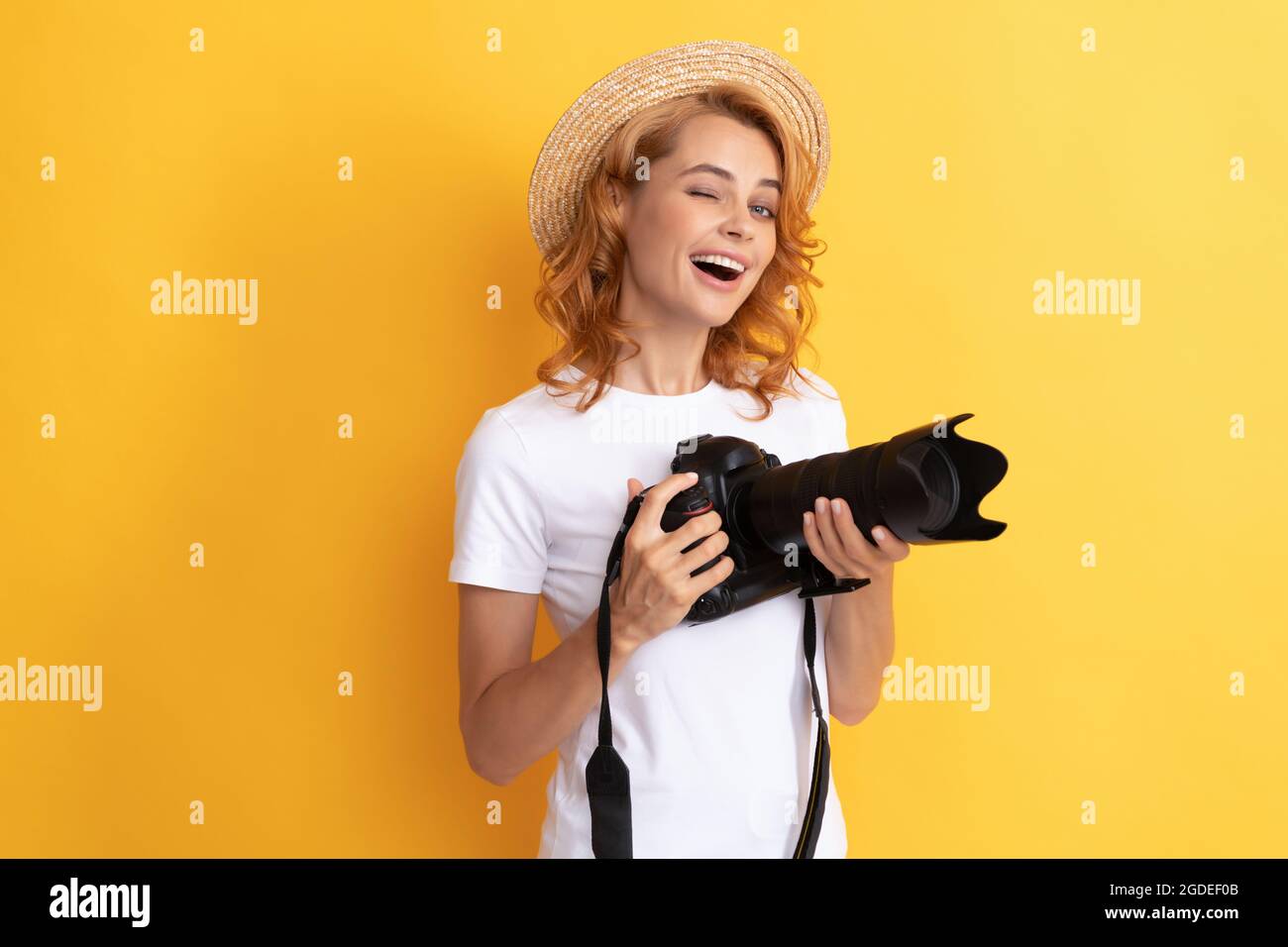 winking fotografo femminile. donna in cappello di paglia fotografando. Foto Stock