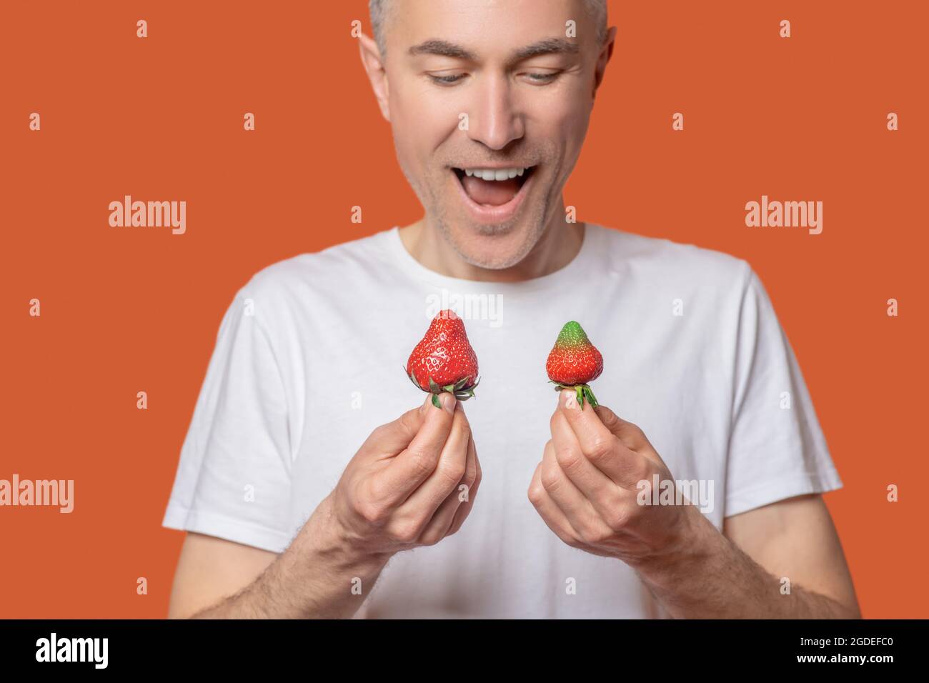 Felice uomo che vuole mangiare fragole Foto Stock