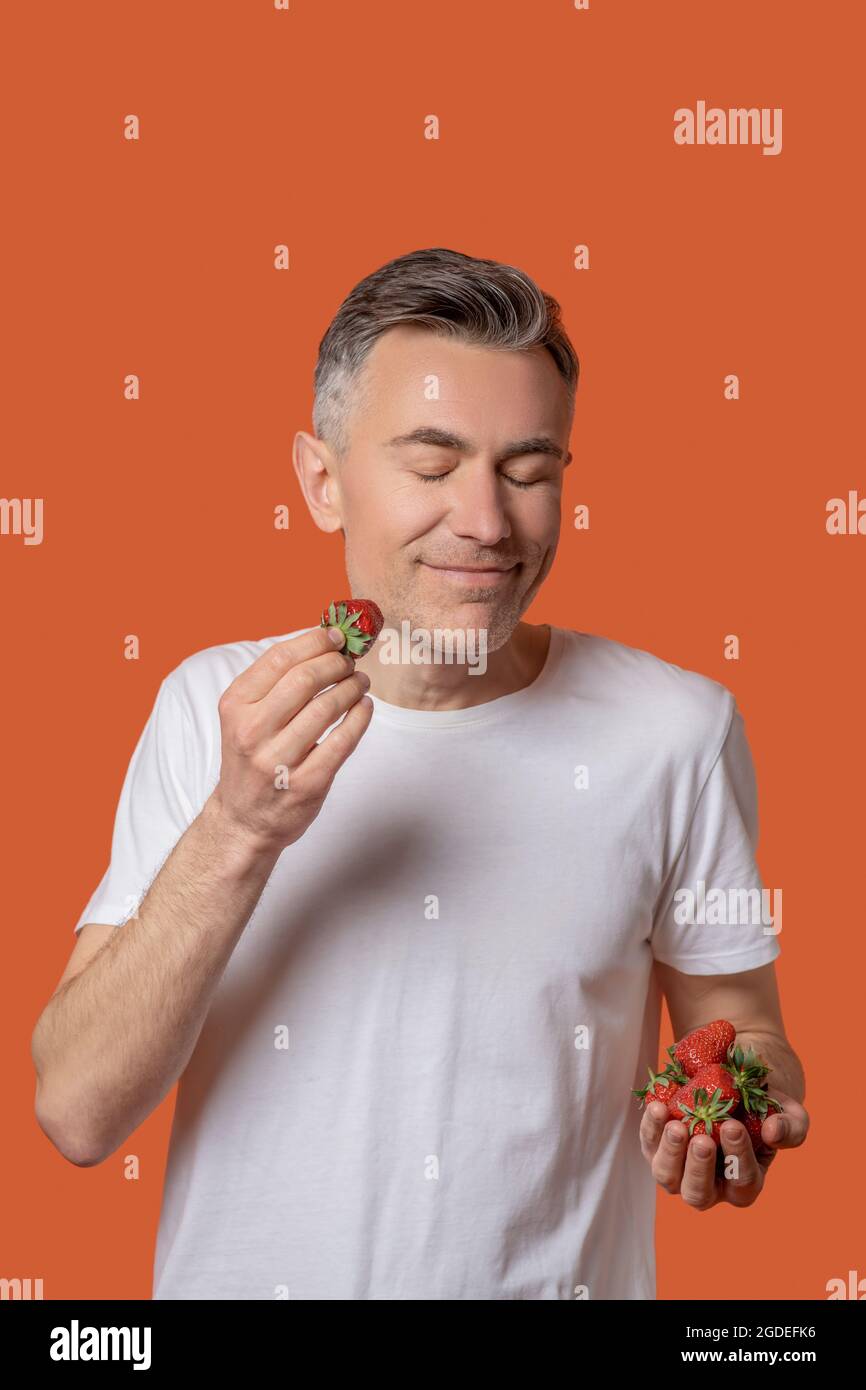 Uomo sorridente con occhi chiusi e fragola Foto Stock