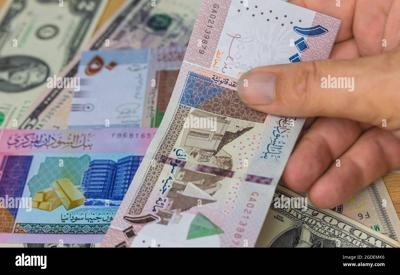 Mano maschile tenere 100 sterline sudanesi banconota, la valuta del Sudan. Primo piano carta denaro del paese arabo con un'inflazione elevata. Mostra mani vecchio uomo Foto Stock