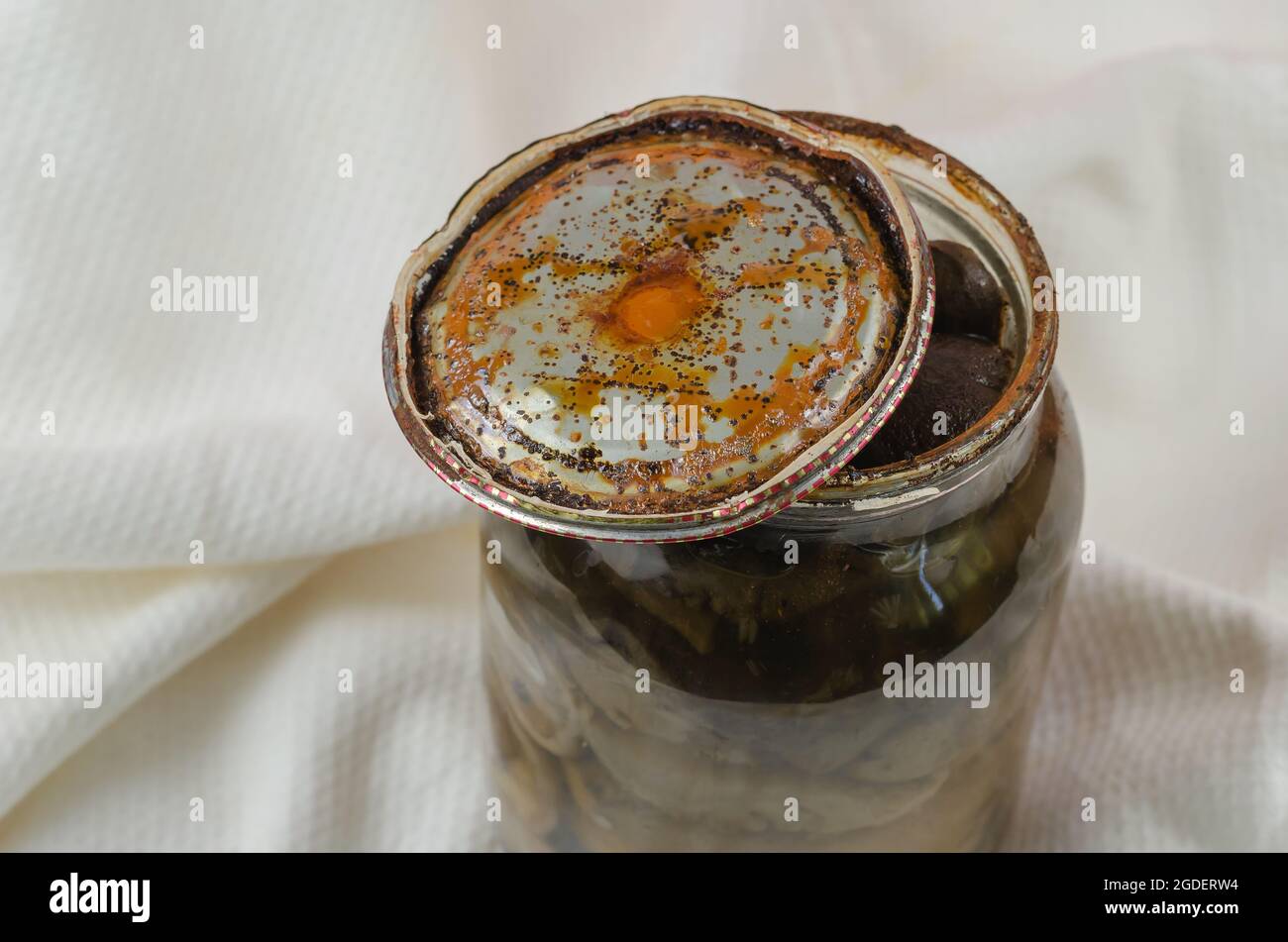 Vaso di vetro aperto con funghi sottaceto fatti in casa. Coperchio in stagno arrugginito con macchie nere. Guastato funghi di foresta anneriti. Botulismo, avvelenamento alimentare da ca Foto Stock