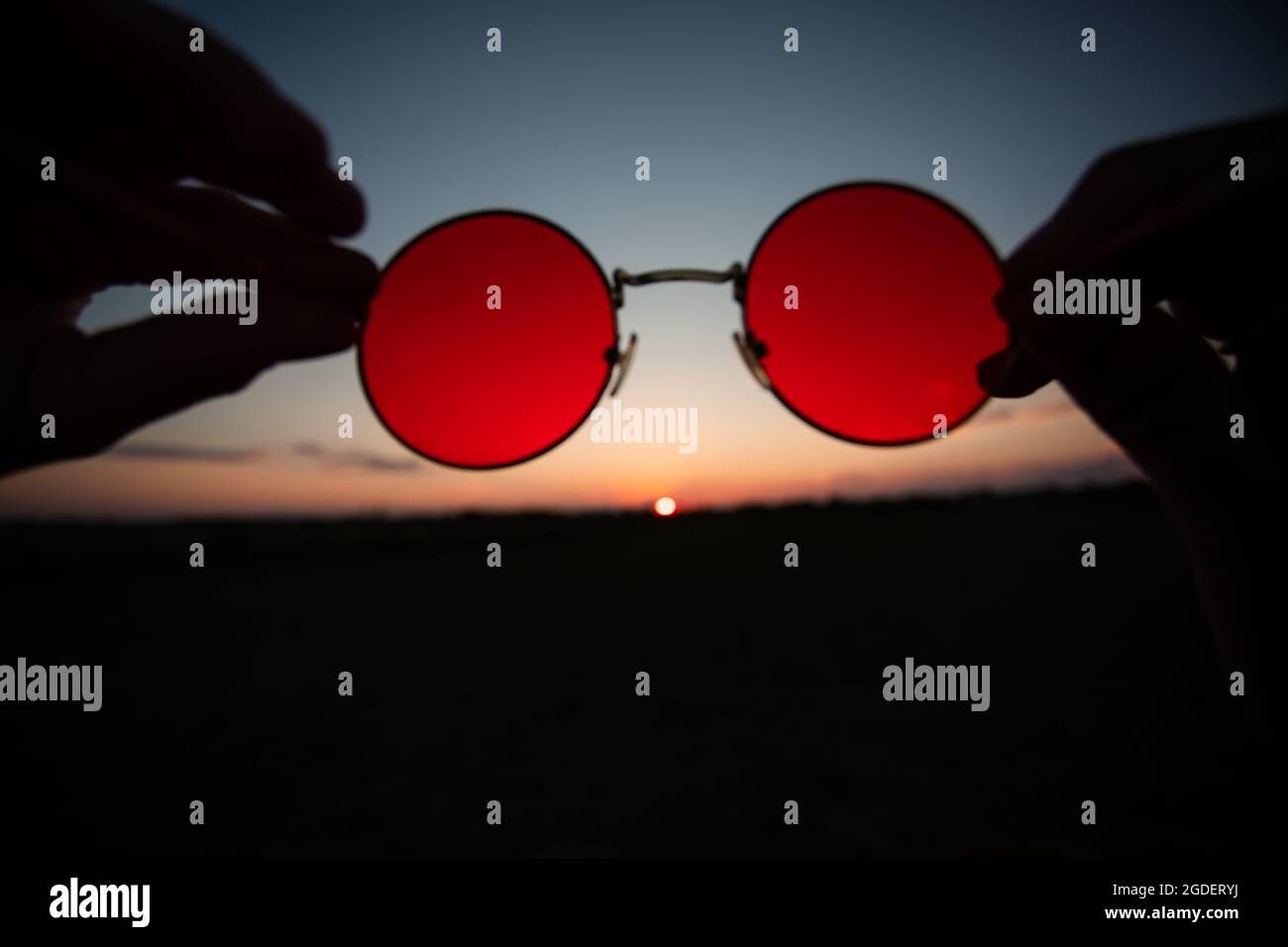 Tramonto estivo attraverso gli occhiali da sole con lenti rosse Foto stock  - Alamy