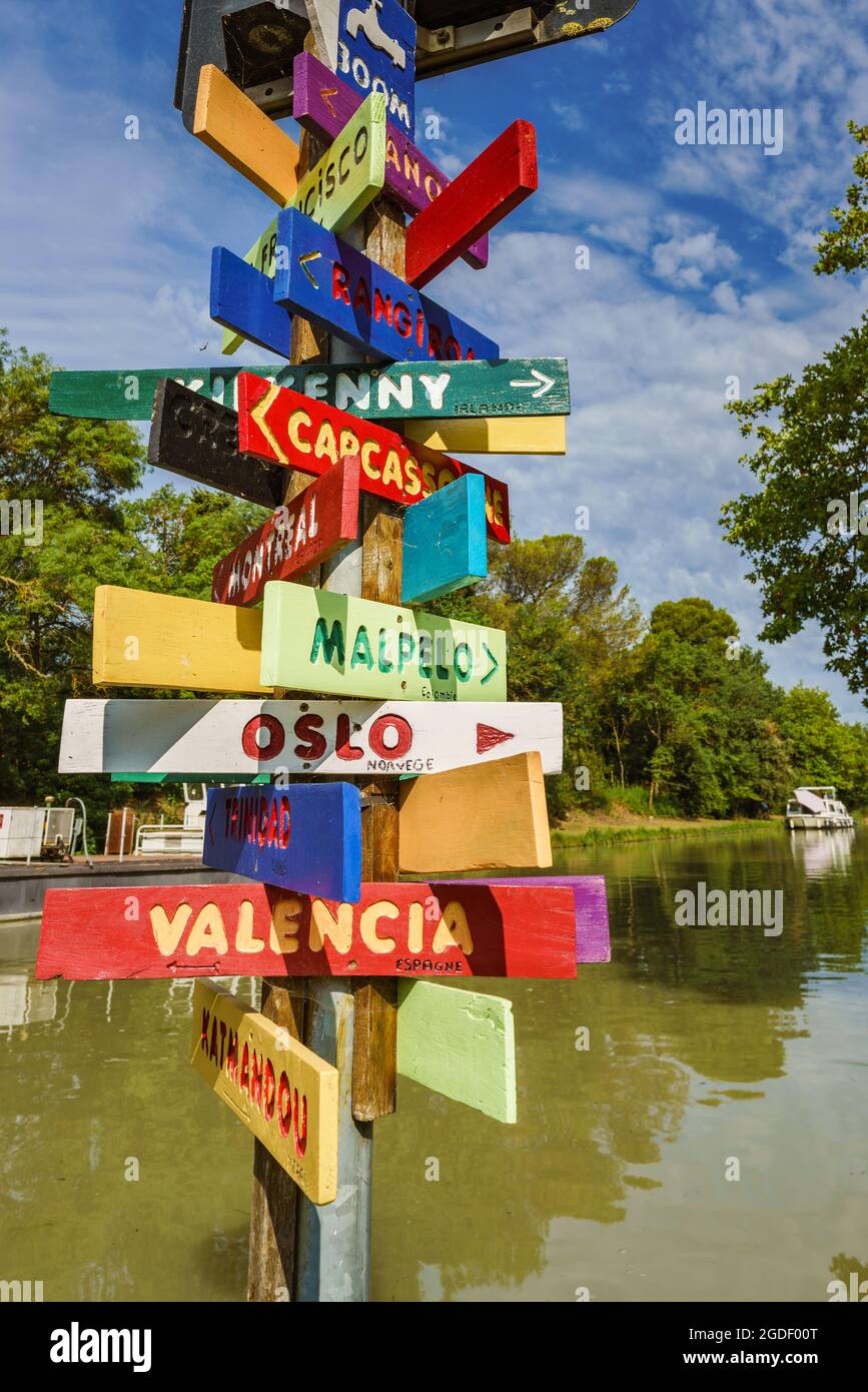 Carcassonne, Francia. Posta con cartelli che indicano la direzione di varie città del mondo con diversi colori sul Canal du Midi Foto Stock
