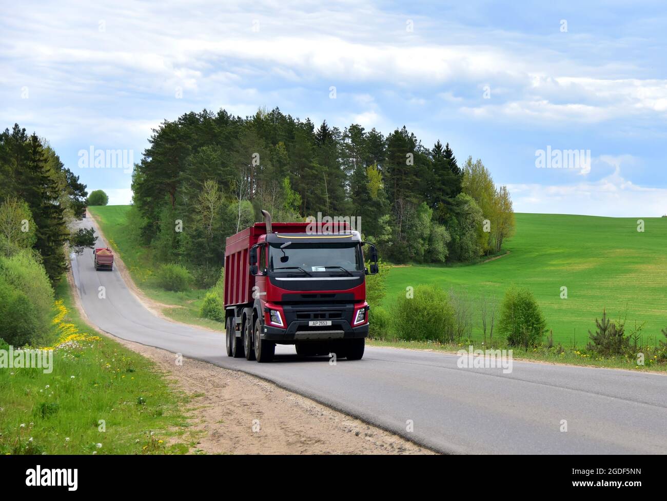 Il dumper ribaltabile trasportava sabbia dalla cava durante la guida su autostrada. Moderno dumper per per impieghi pesanti per il trasporto di carichi sfusi. Camion su strada Foto Stock