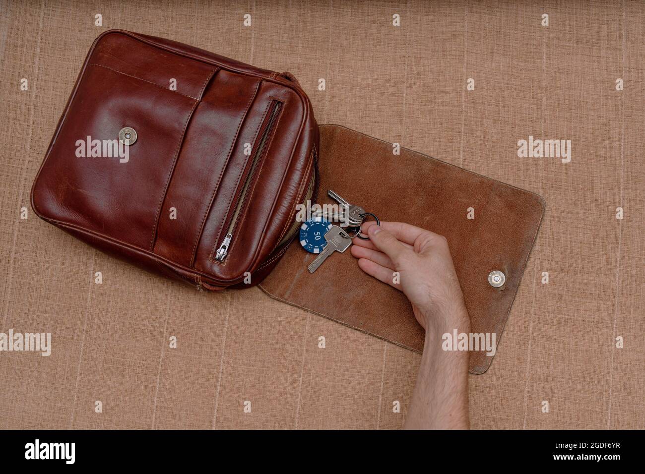 Vista dall'alto di una persona che tacchera le chiavi da una borsa da uomo  marrone in pelle Foto stock - Alamy