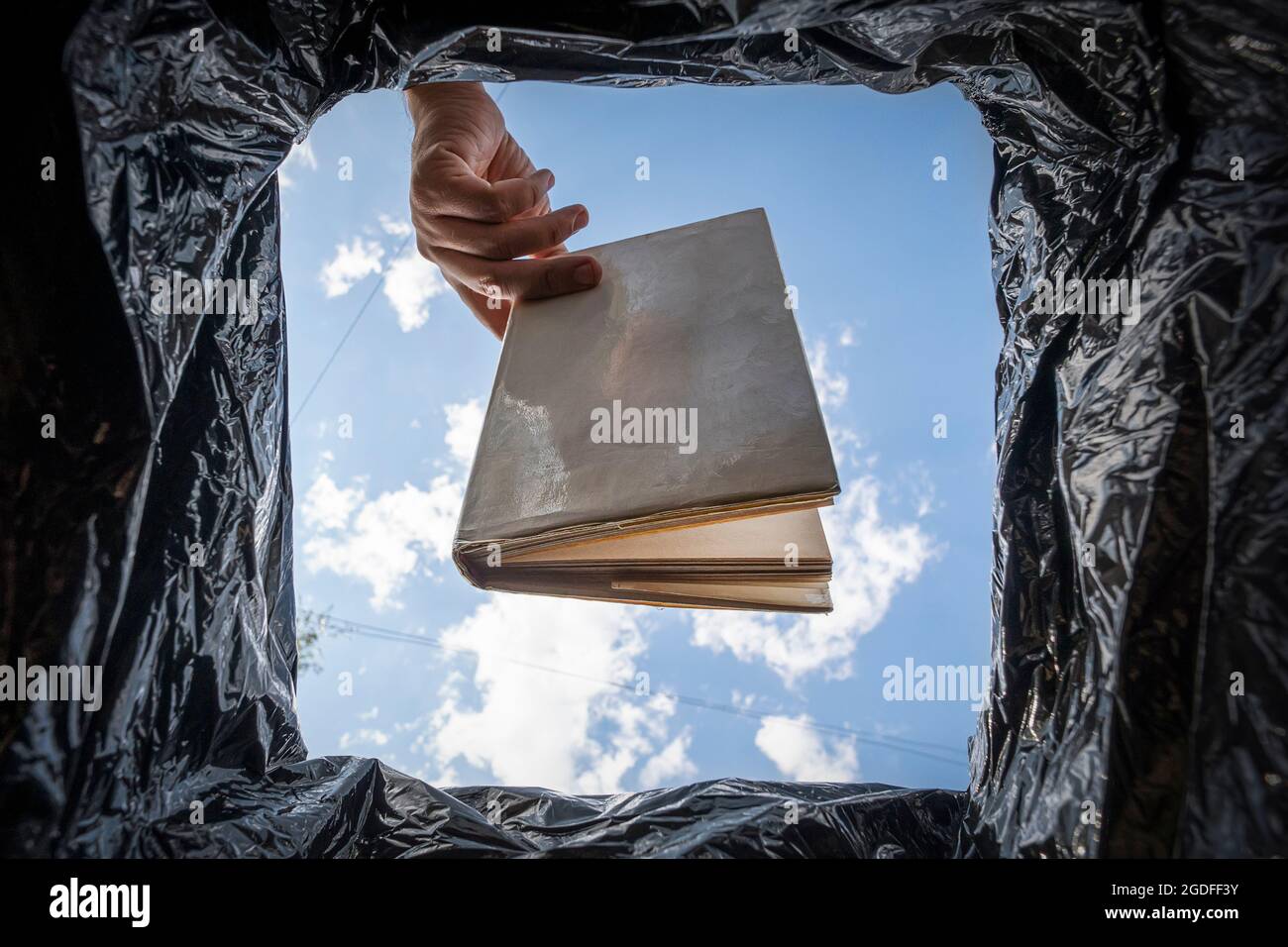 Libro che non legge, letteratura di basso-grado. Un uomo stupido e non istruito getta il suo libro di testo nella spazzatura. Il concetto di cattiva istruzione. Digitalizzazione a Foto Stock