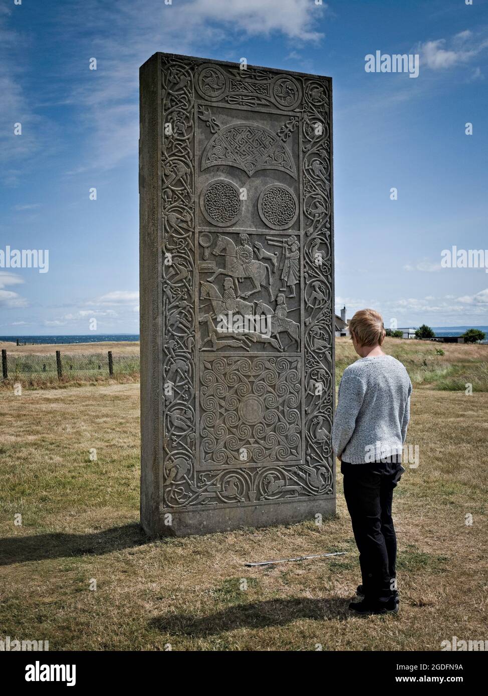 Lady guarda i simboli sul ricostruito Hilton di Cadboll Pictish pietra in piedi Foto Stock