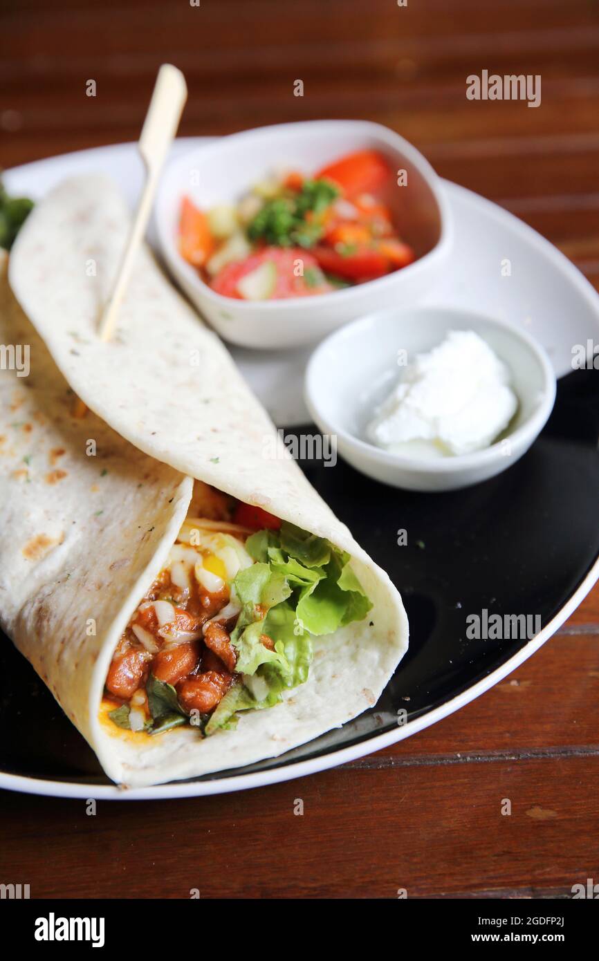 Burritos messicani su un piatto con insalata di pomodoro Foto Stock