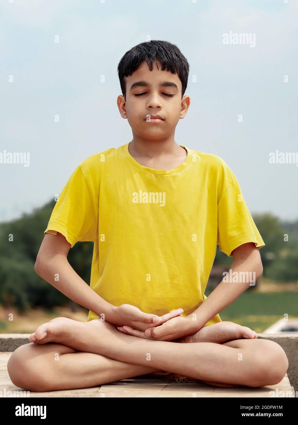Un bambino carino indiano giovane facendo yoga posa di loto (padmasana). Foto Stock