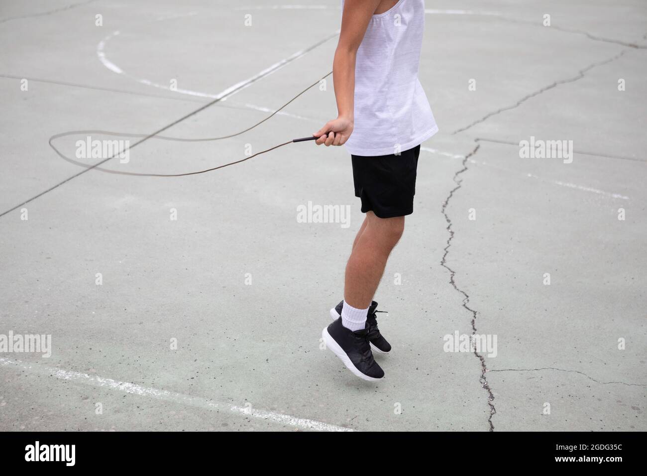 Un adolescente di sesso maschile del giocatore di basket sul campo da pallacanestro saltando il collo verso il basso Foto Stock