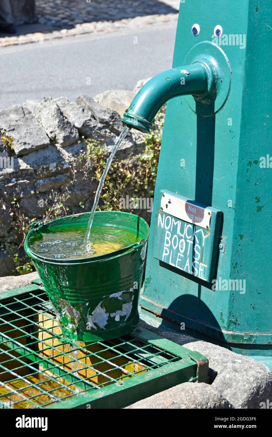 Primo piano di acqua che scorre verde Grassington villaggio pompa con palle occhio e avviso circa Dale walkers stivali fangdy Wharfedale North Yorkshire Inghilterra Regno Unito Foto Stock
