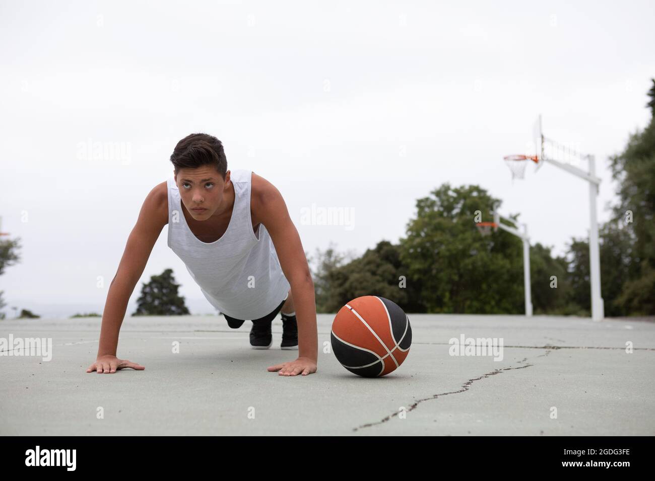 Un adolescente di sesso maschile del giocatore di basket sul campo da pallacanestro facendo ups push Foto Stock