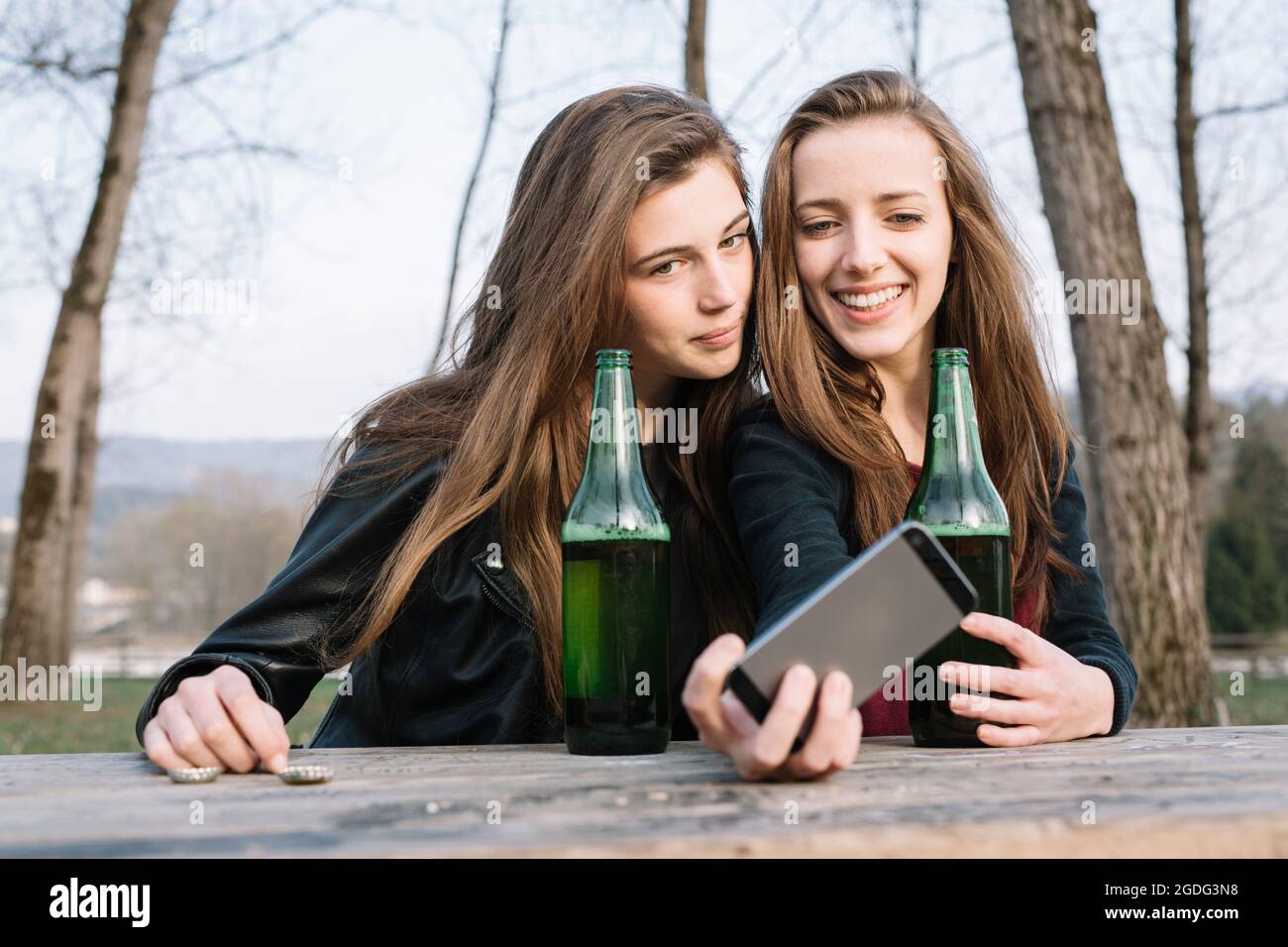 Fidanzate tenendo selfie con la birra in posizione di parcheggio Foto Stock