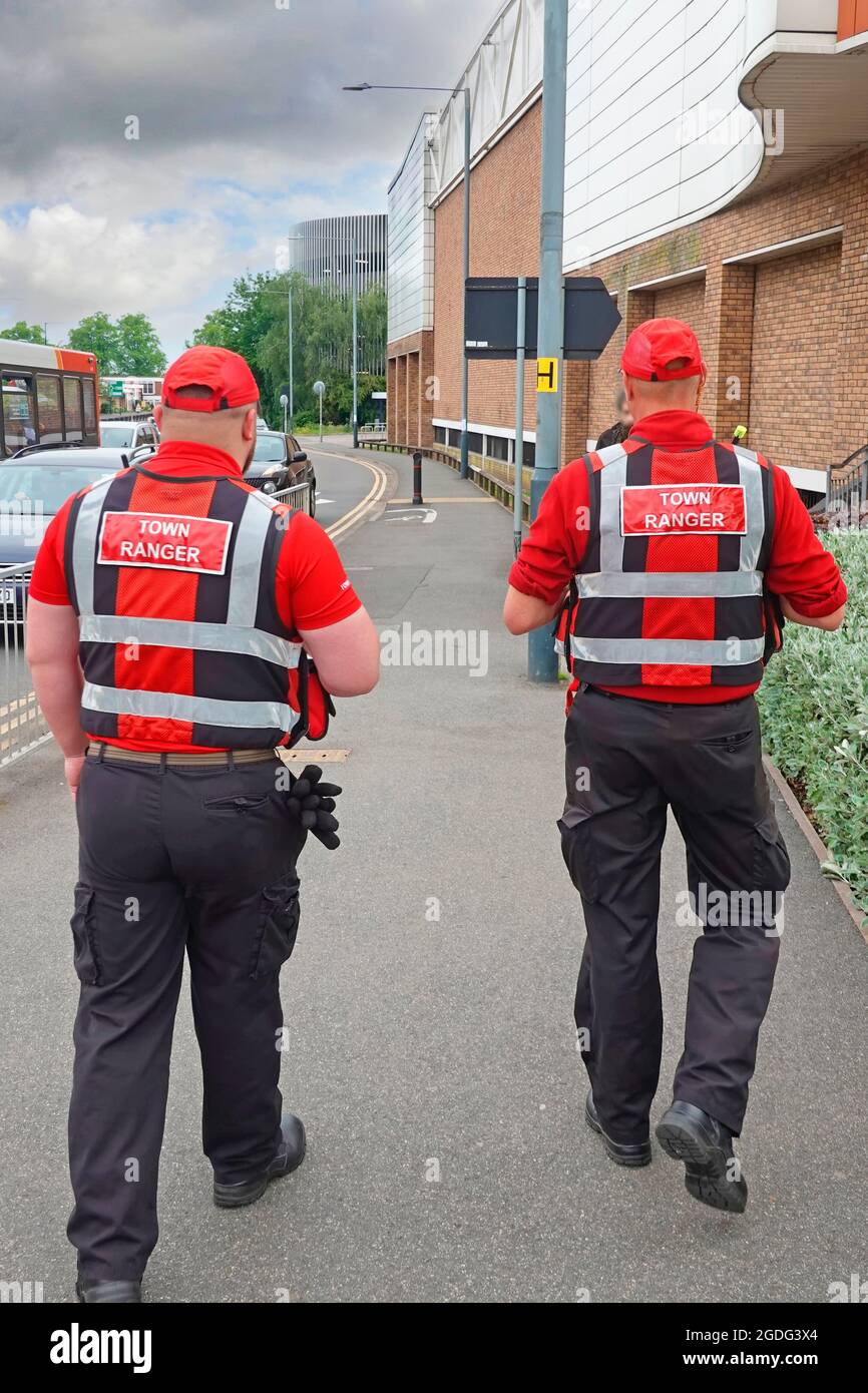 Due Rugby Town Rangers in rosso uniforme pattugliando centro città di targeting attività criminale collegamenti radio diretti a operatori CCTV e polizia Warwickshire UK Foto Stock