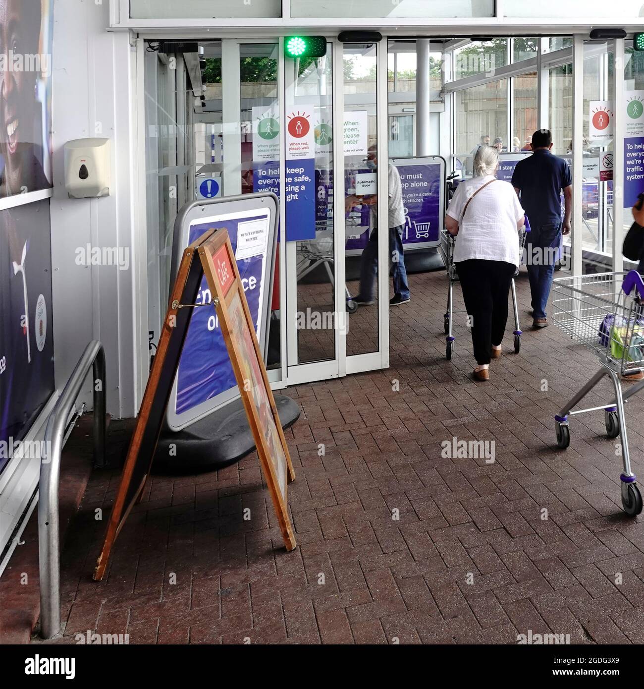 Tesco Supermarket store porta scorrevole ingresso a una via sistema di semafori conteggio acquirenti entrata evitando di affollarsi in Covid 19 pandemic Inghilterra UK Foto Stock