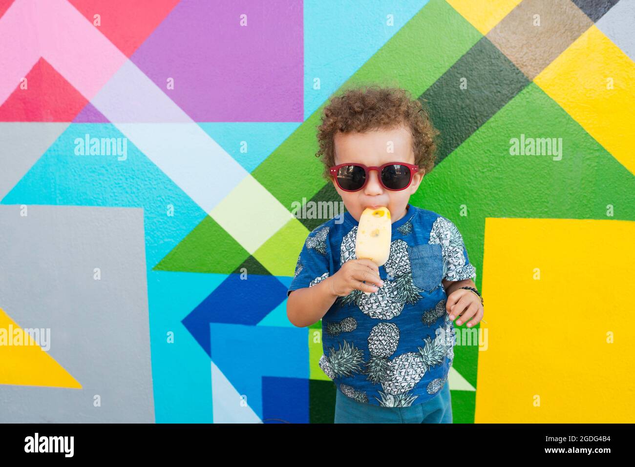 Bambino a mangiare il gelato, murale in background, Wynwood, Miami, Florida, Stati Uniti d'America Foto Stock