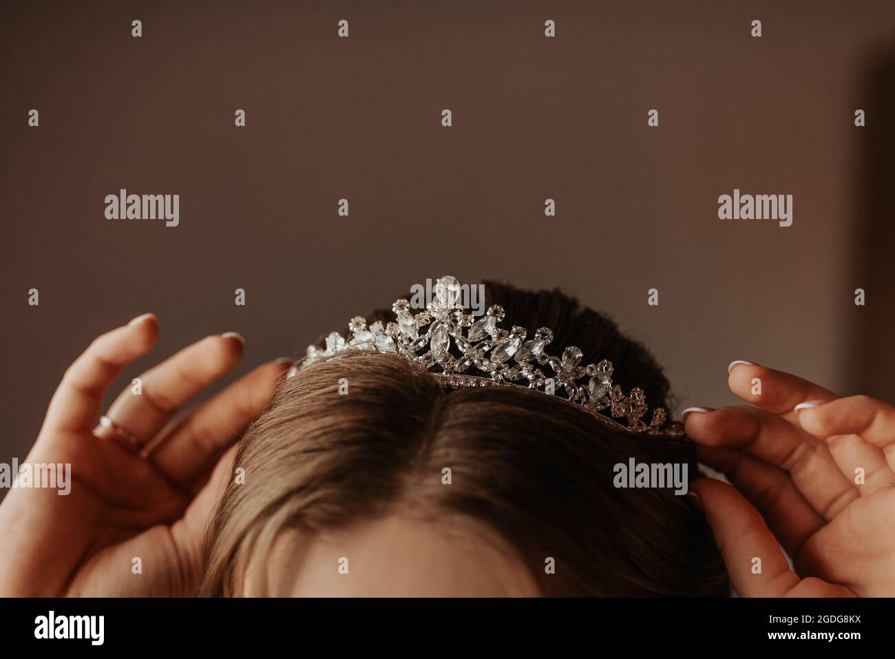 la ragazza tiene sulla testa una corona tiara decorata con pietre preziose, la giovane sposa raddrizza gli accessori sulla testa e sulle orecchie Foto Stock