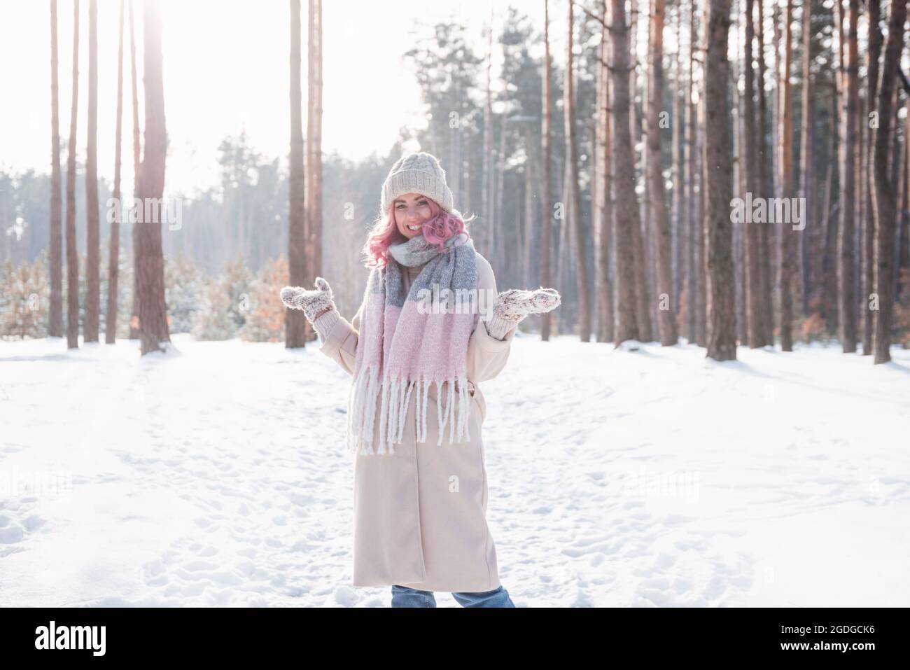 Donna d'inverno che guarda felice e sorridente all'aperto nella neve in freddo giorno d'inverno Foto Stock