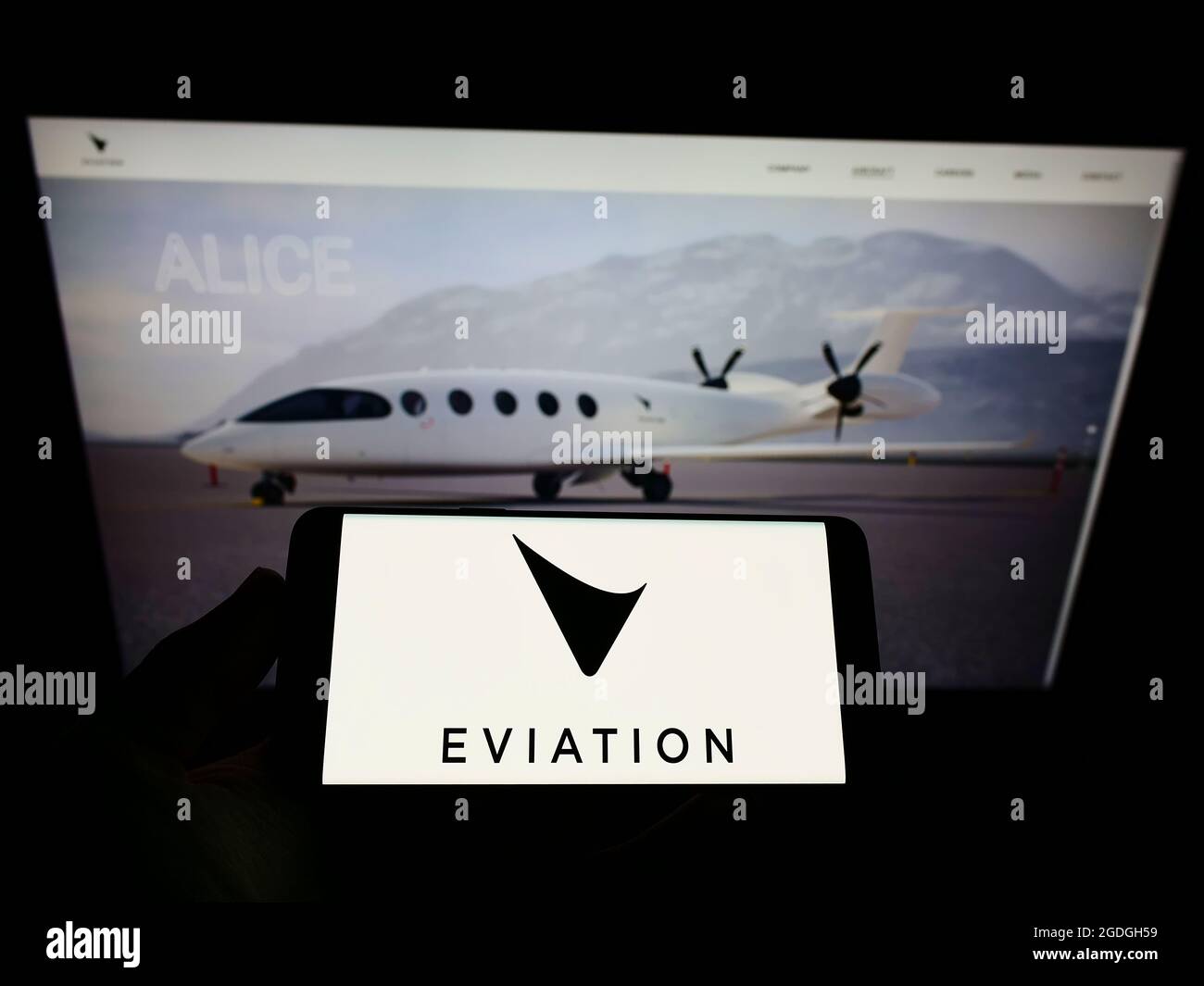 Persona che tiene il telefono mobile con il logo della società di aeromobili elettrici Eviation Aircraft Ltd. Sullo schermo davanti alla pagina web. Mettere a fuoco il display del telefono. Foto Stock