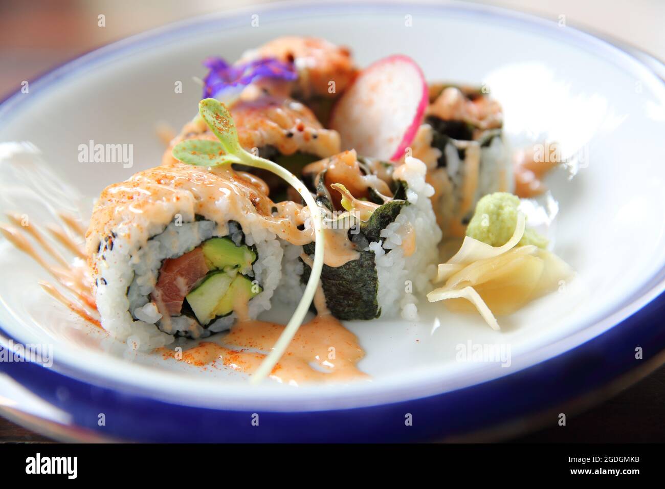 tonno al salmone e uramaki all'avocado con salsa piccante in primo piano Foto Stock