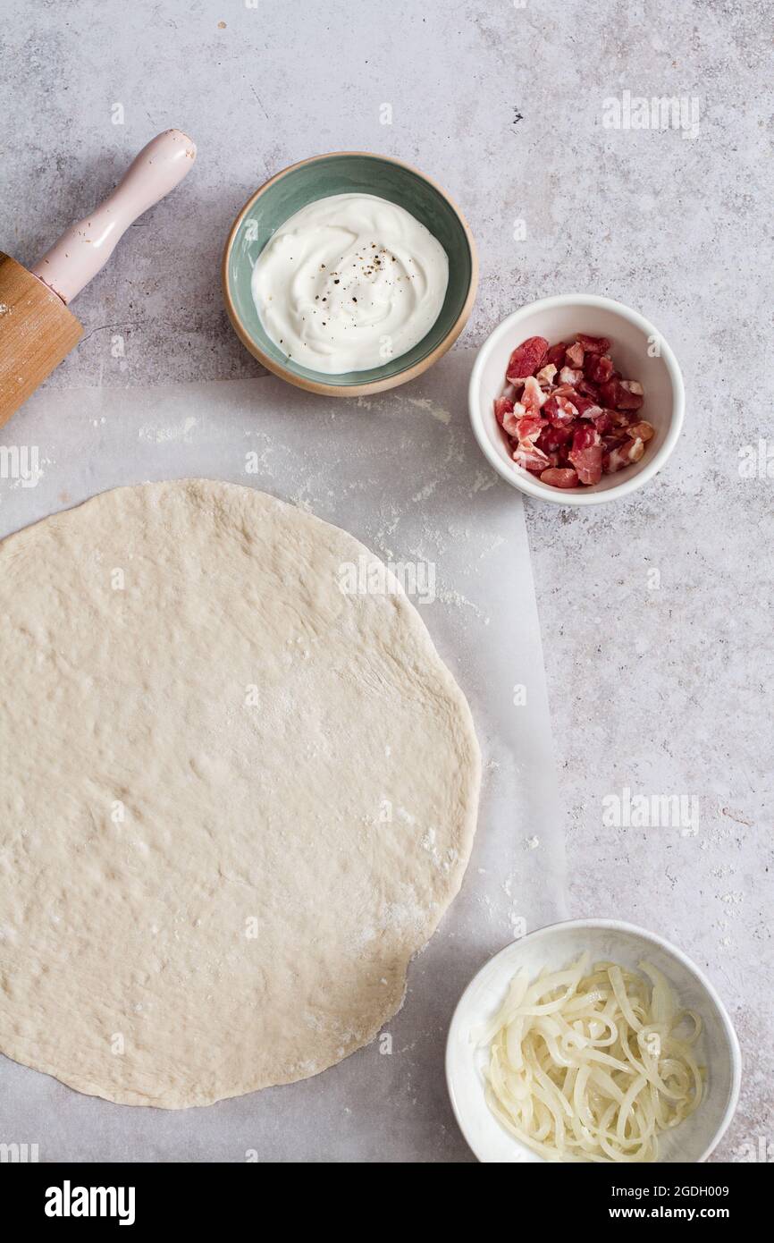 Fare un tarte flambee (flammkuchen) con crema fraiche, fromage blanc, larcon e cipolla. Foto Stock