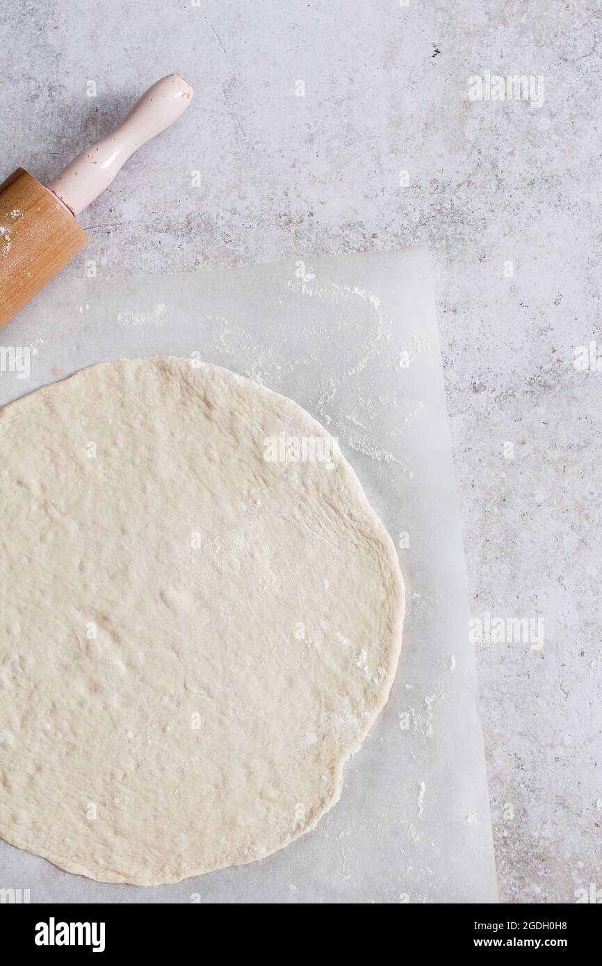 Pasta di pane o pasta di pizza che viene arrotolata con un mattonello per fare tarte flambee o flammkuchen. Foto Stock