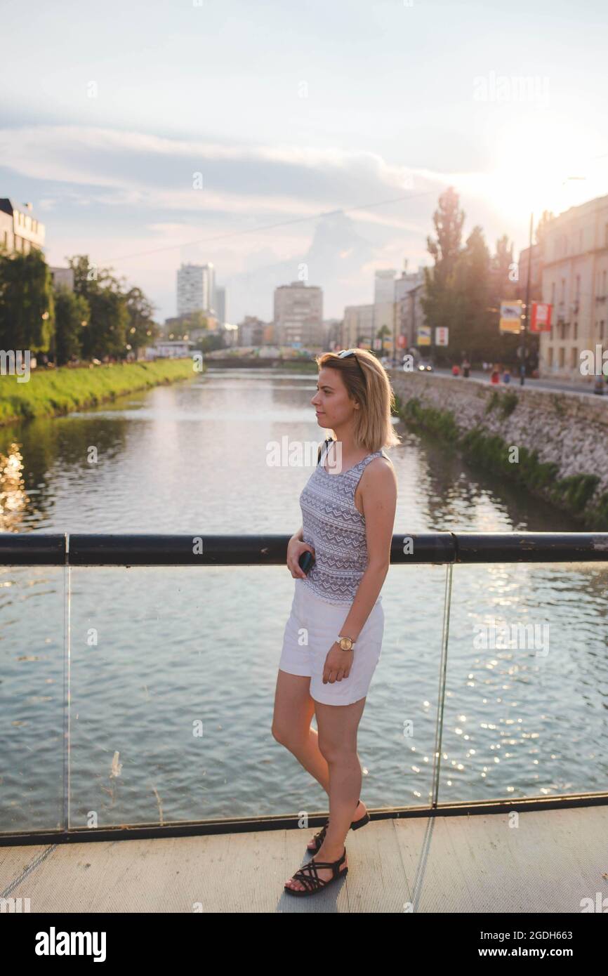 Immagine verticale di una giovane viaggiatore europea su un ponte su un fiume in una giornata di sole Foto Stock