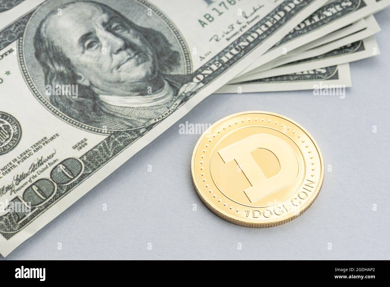 Moneta di Dogecoin e un mucchio di banconote in dollari USA. Blockchain money vs. fiat money Concept Foto Stock