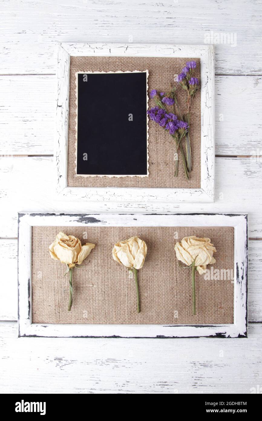 Cornici in legno con fiori secchi e foto in bianco su sfondo in legno Foto Stock