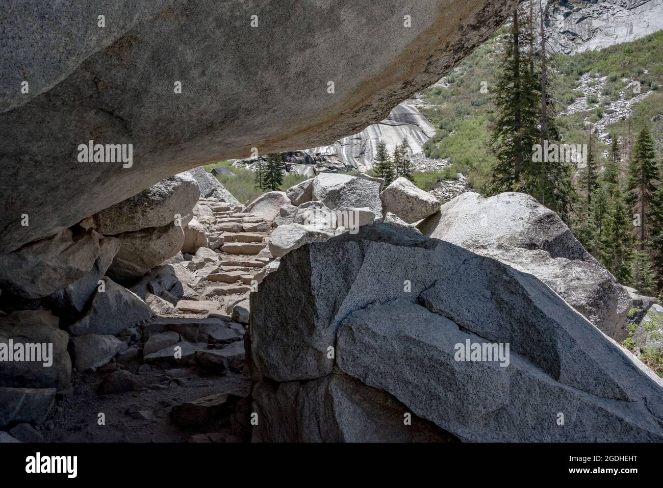 Gli escursionisti devono anatra mentre passano sotto questo enorme masso di granito che sovrasta il Tokopah Falls Trail nel Sequoia National Park. Dall'altro Foto Stock
