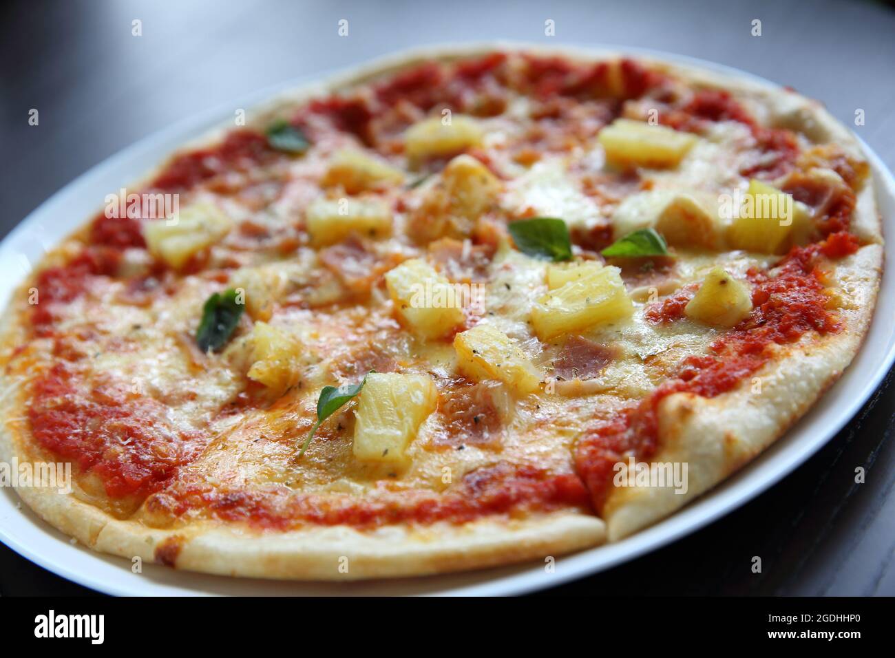 Pizza hawaiana, pizza con prosciutto formaggio ananas su sfondo legno Foto Stock