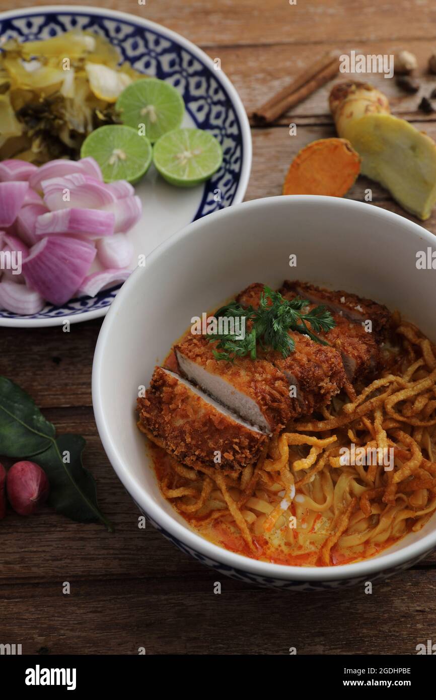 Cibo locale della Thailandia del nord al curry all'uovo con maiale fritto su sfondo di legno Foto Stock