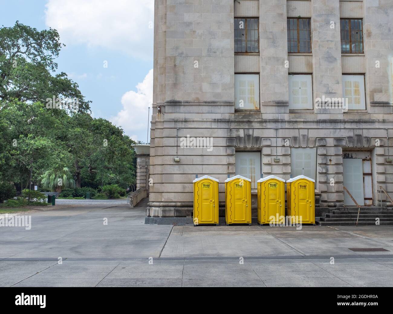 New Orleans, LA, USA - 7 agosto 2021: Quattro bagni portatili Yellow Pot-o-Gold accanto all'auditorium municipale Foto Stock