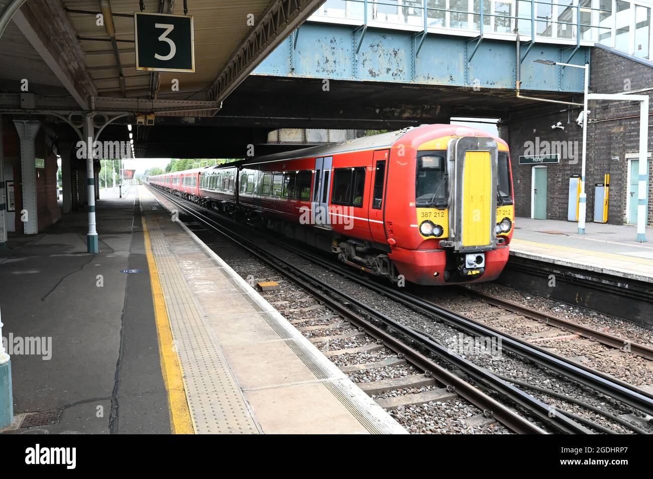 Un treno per pendolari passa attraverso la stazione di Horley con il Gatwick Express Branding. Foto Stock