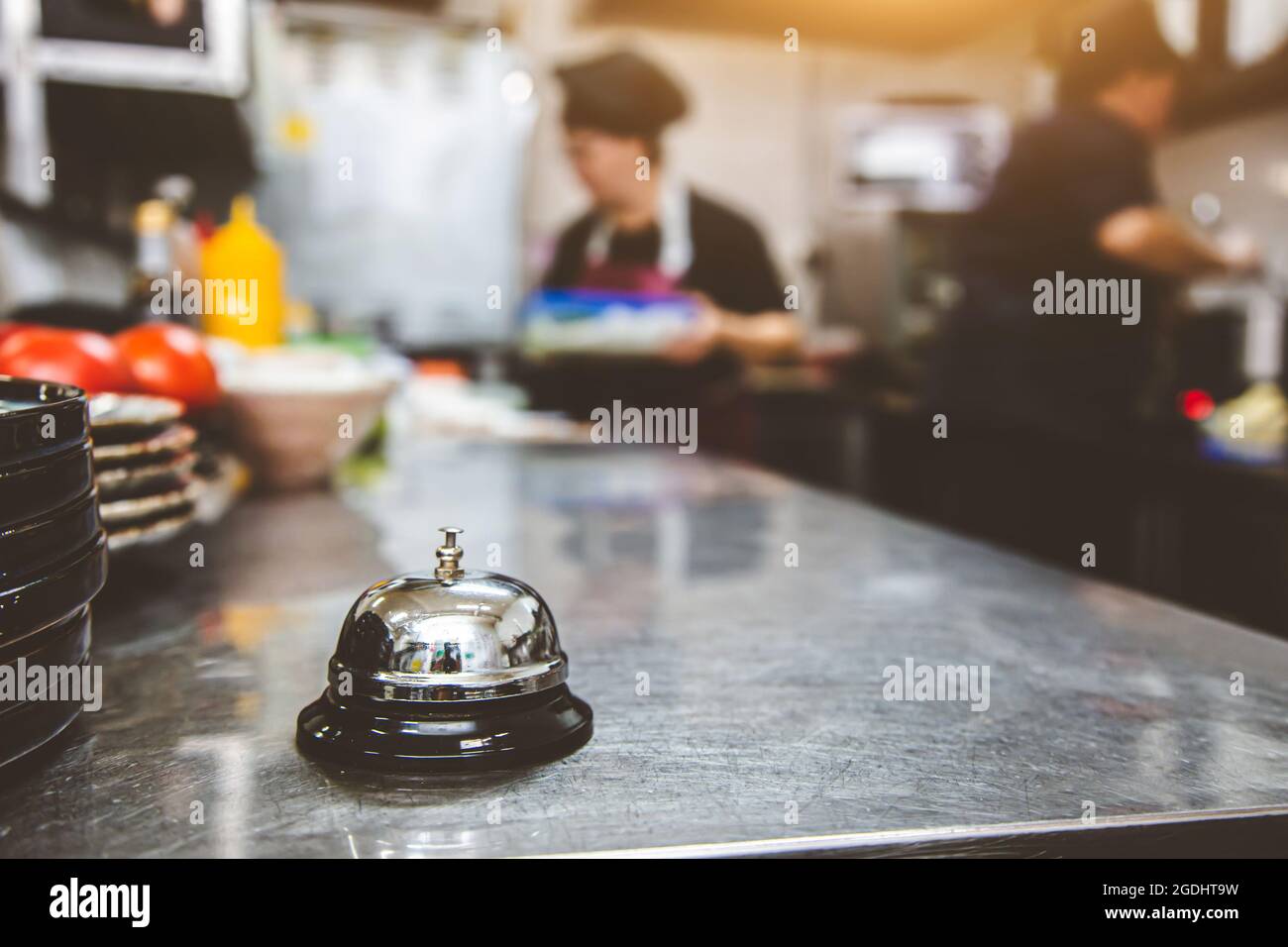 Silver Call Bell sul tavolo, chef in un ristorante sullo sfondo. Cucina in cucina. Foto Stock