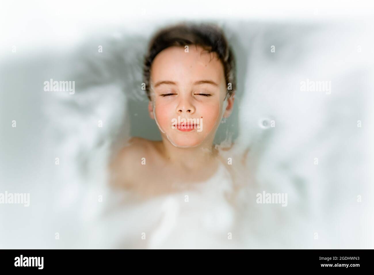 8 anni bel ragazzo nel bagno occhi chiusi Foto Stock