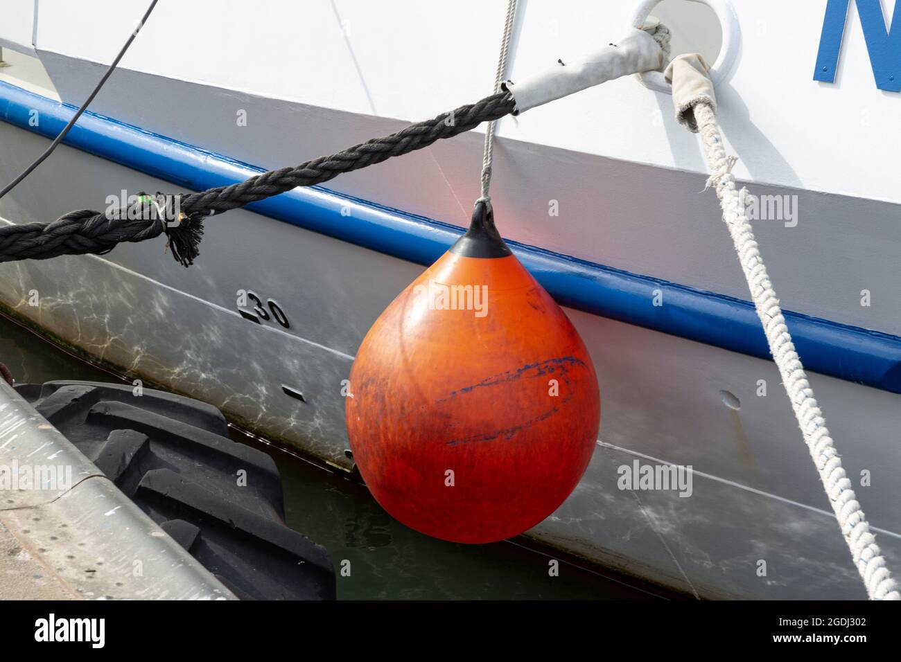 Una boa arancione pende sul lato di una barca. Foto Stock