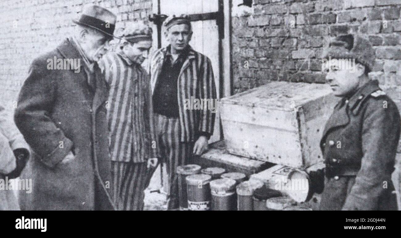 Ufficiale sovietico ed ex prigionieri del campo di concentramento di Auschwitz II (Birkenau) vicino a scatole con contenitori wit. Foto Stock