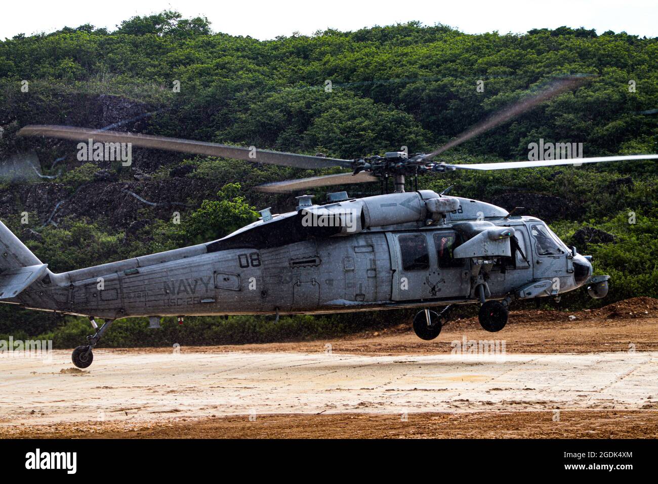 210803-N-MO469-1012 SANTA RITA, Guam (agosto 3, 2021) l'equipaggio assegnato all'HSC-25 atterra un MH-60S su un pattino di atterraggio prototipo costruito da Seabees assegnato a Naval Mobile Construction Battaglione (NMCB) 11 Det. Guam. Il pianerottolo è stato costruito mentre supportava III MEF utilizzando un sistema di applicazioni biocemente sviluppato da bioMASON con il supporto della Defense Advanced Research Projects Agency. Il sistema di applicazione biocemento è progettato per essere utilizzato in posizioni operative in avanti su superfici native non ingegnerizzate per rafforzare il terreno, promuovere il controllo dell'erosione e aumentare il disbimento della polvere migliorando exdi Foto Stock