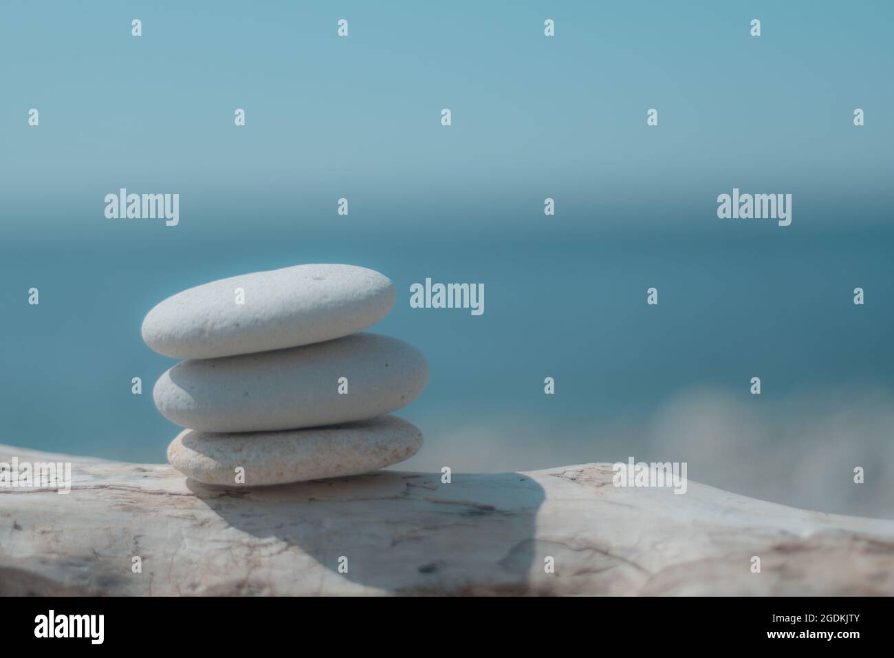 Equilibrata piramide di ciottoli sulla spiaggia in una giornata di sole. Abstract Sea bokeh sullo sfondo. Messa a fuoco selettiva. Pietre Zen sulla spiaggia di mare, meditazione Foto Stock