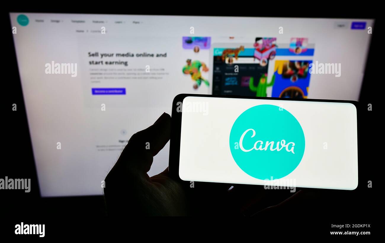 Persona che tiene smartphone con il logo della società australiana di disegno grafico Canva Pty Ltd sullo schermo di fronte al sito web. Mettere a fuoco il display del telefono. Foto Stock