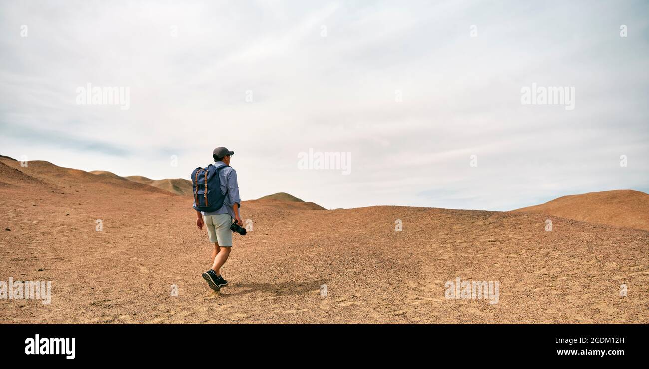asiatico uomo zaino in spalla fotografo paesaggio a piedi su una collina guardando vista, vista posteriore Foto Stock