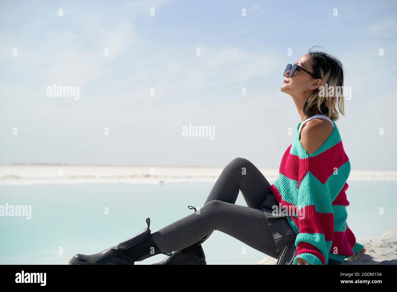 vista laterale di una donna turistica asiatica seduto accanto a un lago salato che guarda alla vista Foto Stock